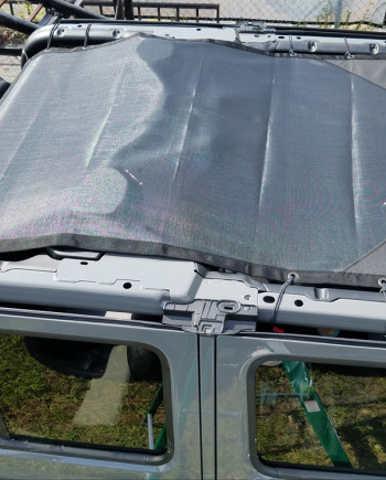Mesh sunshade installed on the roof of a Jeep Wrangler, viewed from above, with partially open retractable top.